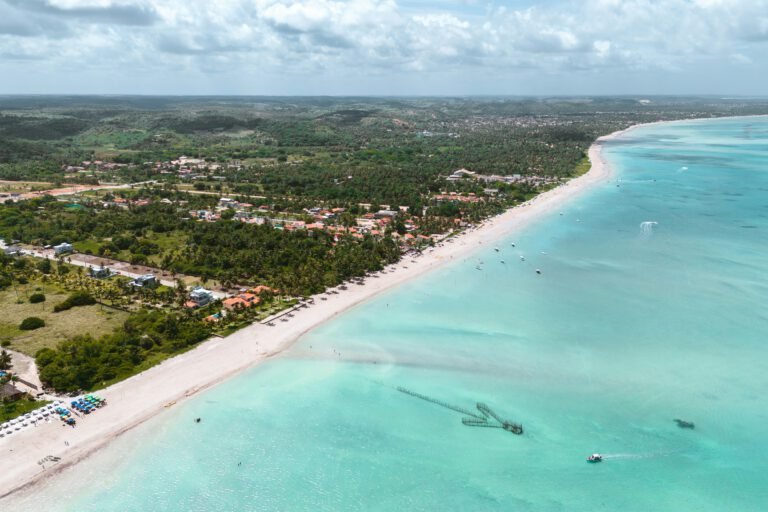 Vista aérea da praia de Maragogi, em Alagoas, com mar azul-turquesa e areia branca, representando o charme do “Caribe brasileiro”.