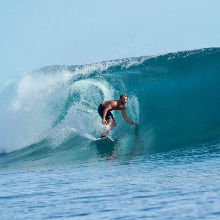 Surfista dentro do tubo em uma onda azul cristalina, representando o surf no Brasil e suas praias paradisíacas.
